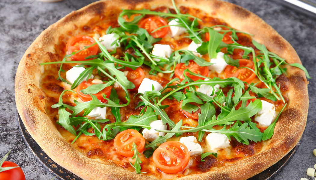Pizzadam pizza closeup met rucola en tomaten